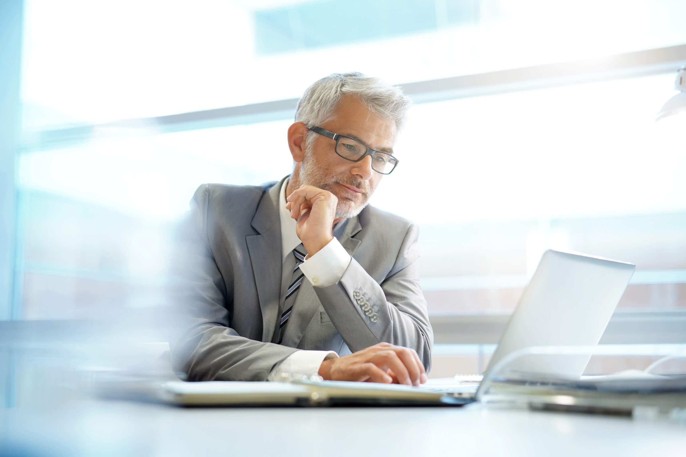  mature businessman with glasses typing on laptop
