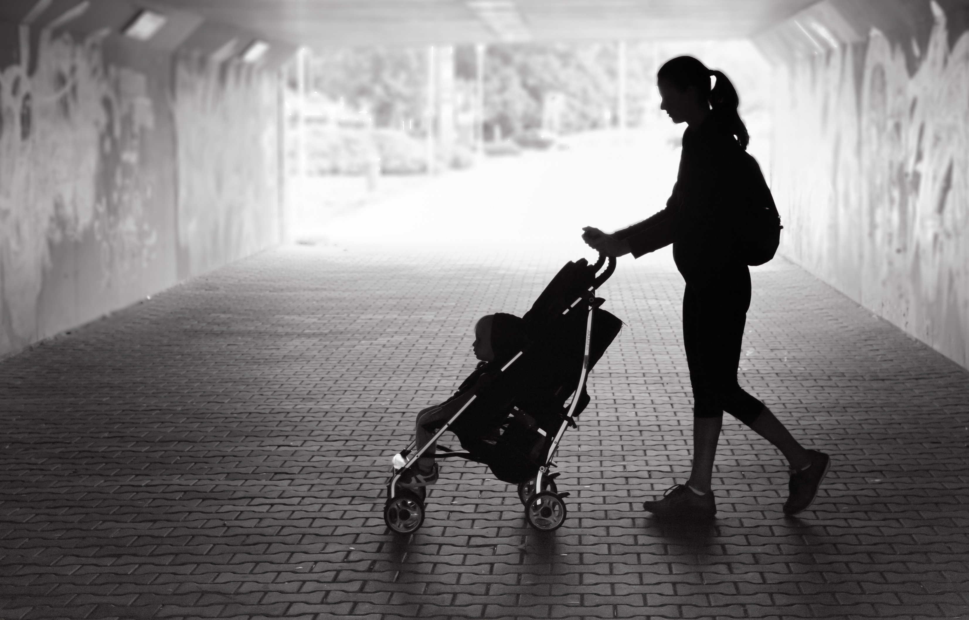 silhouette of mother pushing toddler in baby stroller