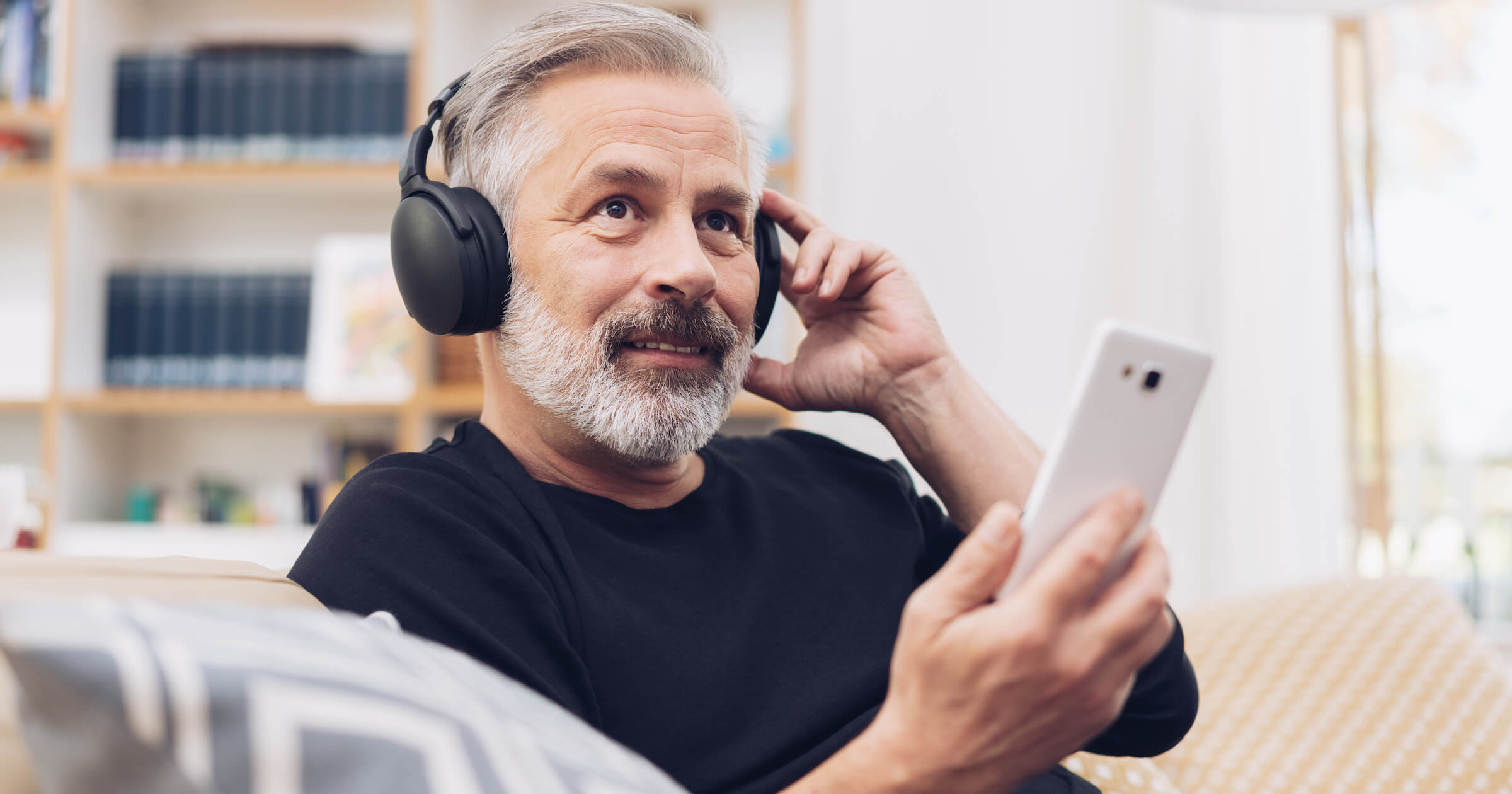  Man with headphones listening to a podcast on his phone